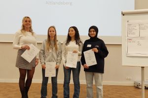 Eine Lehrkraft und vier Schülerinnen der Fachtagung stehen mit ihren Zertifikaten vor einer Leinwand.